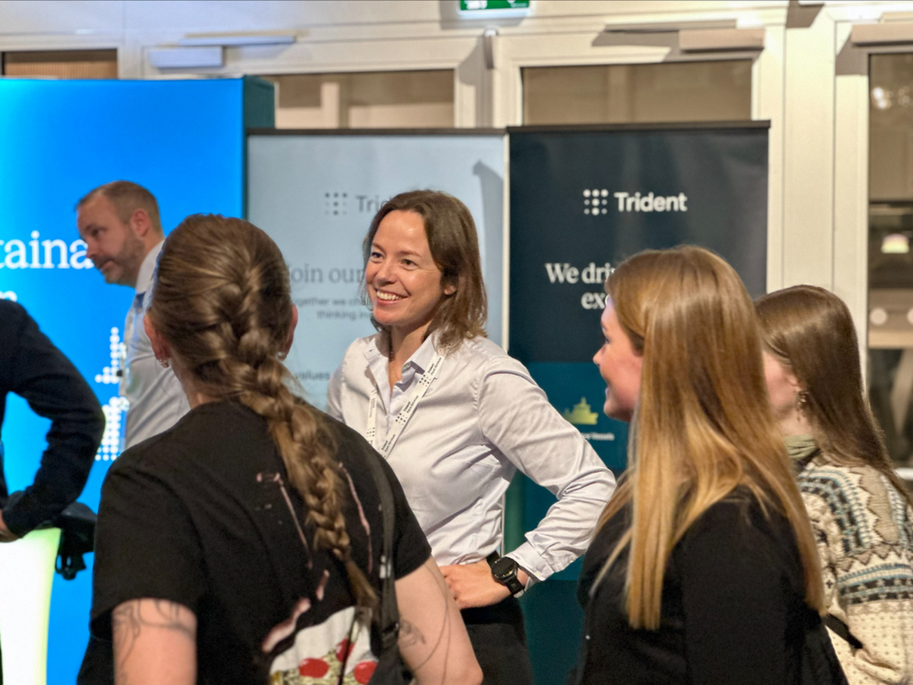 Kvinne som står på stand, smiler og smakker med potensielle arbeidstakere